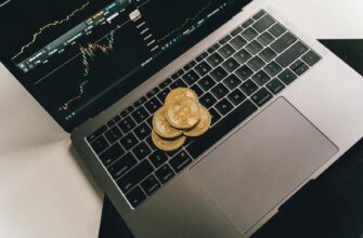 Bitcoin coins placed on a laptop keyboard while a trading chart displays on the screen, showcasing digital finance.