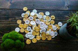 Gold and silver bitcoin coins mixed on a wooden surface with potted plants.