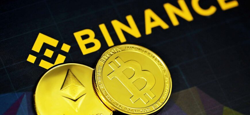 two gold bitcoins sitting next to a binance sign